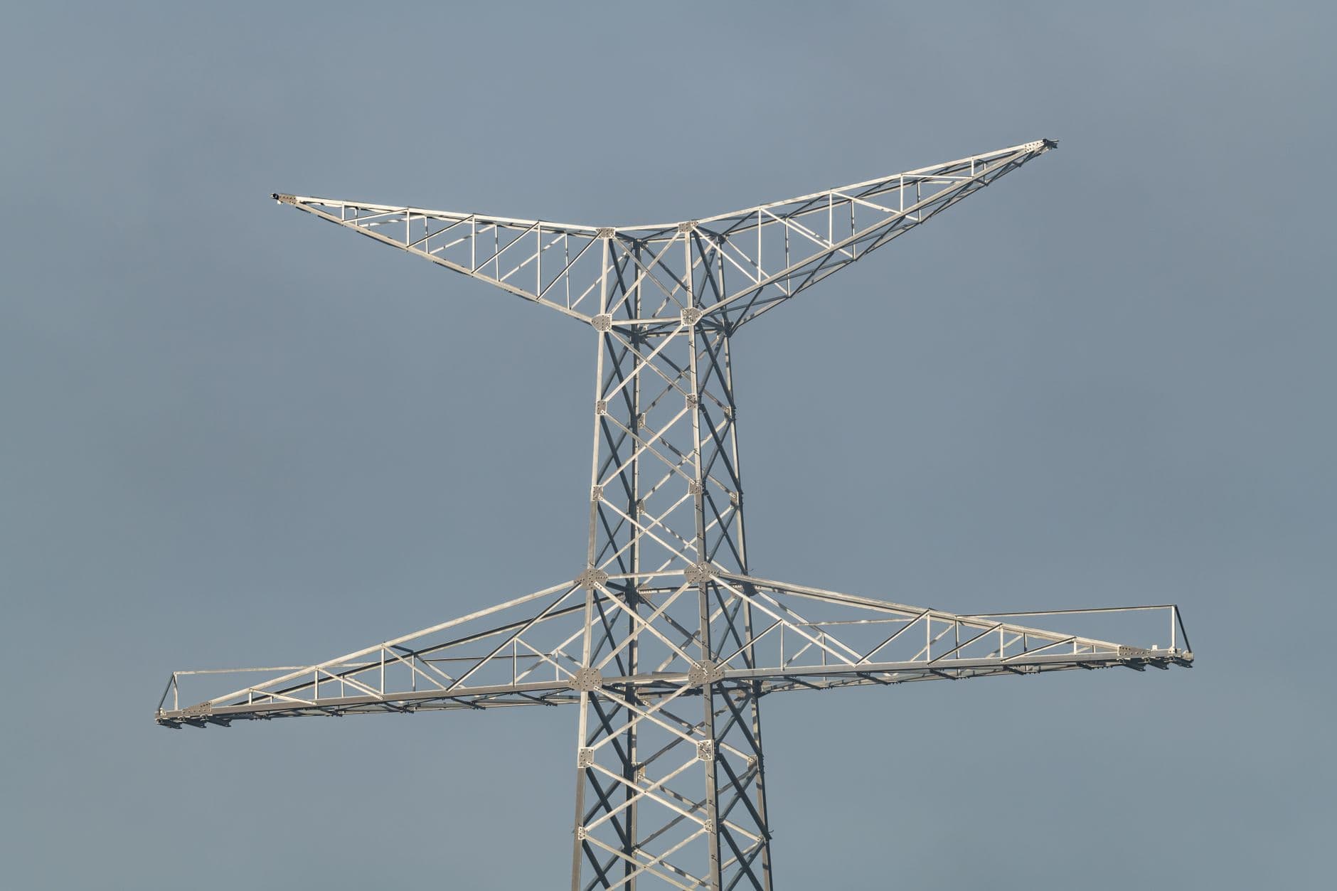 High transmission tower stretching into a clear blue sky, showcasing modern infrastructure.