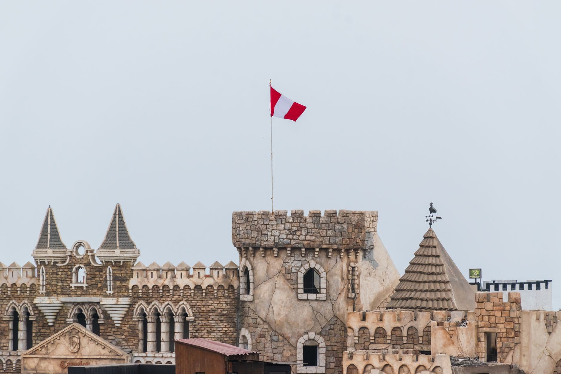 Gothic-style castle with Peruvian flag against sky in Chancay, Lima Region, Peru.