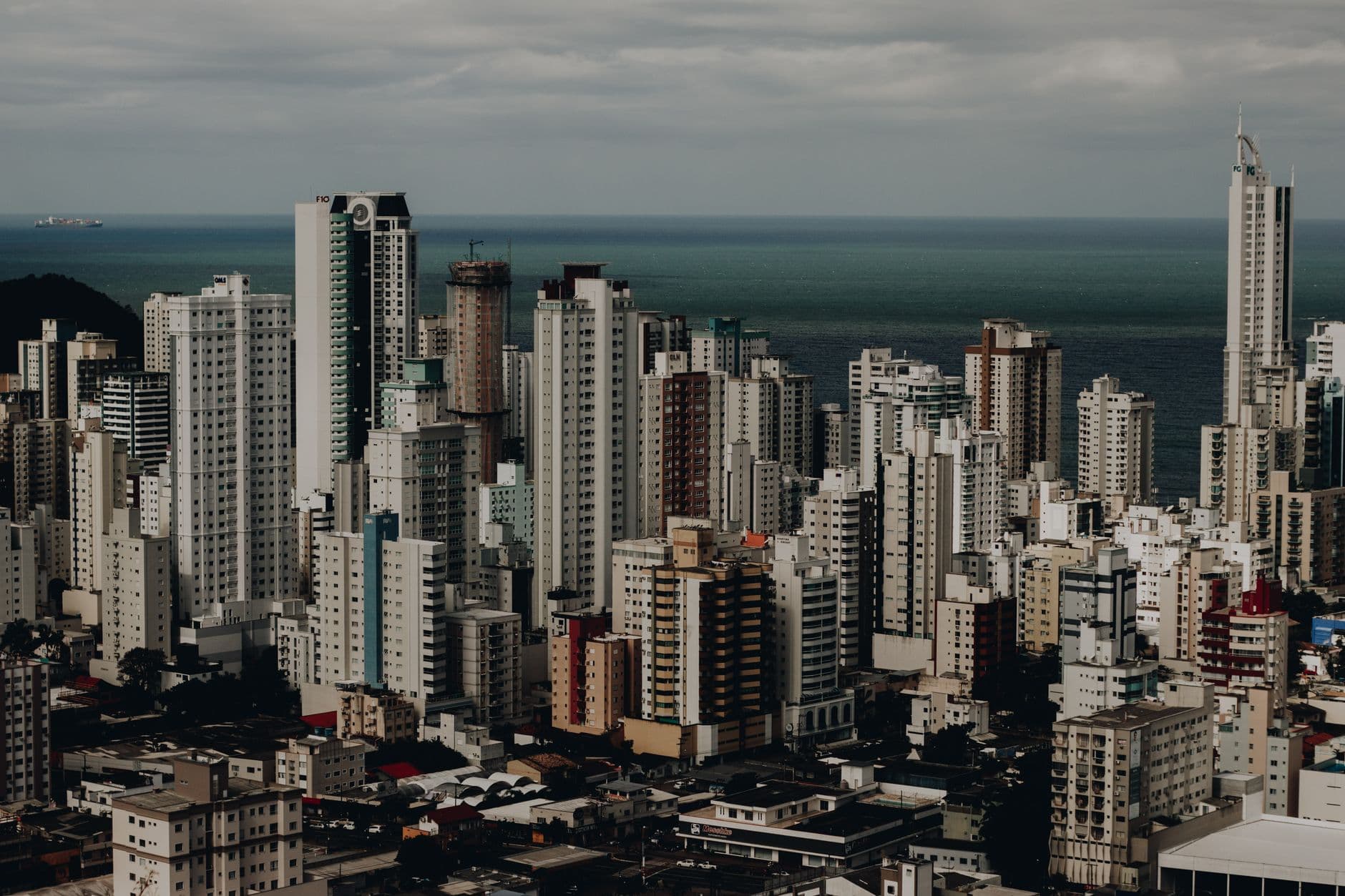 Aerial view of a modern urban skyline with tall skyscrapers overlooking the ocean.