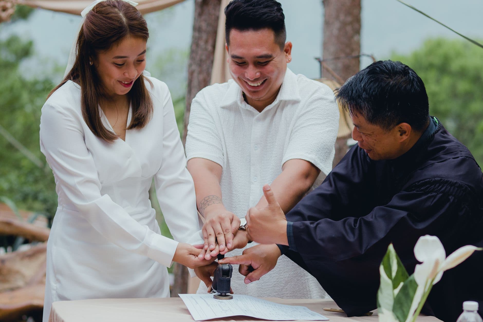 A joyful couple finalizing their wedding with the officiant outdoors.