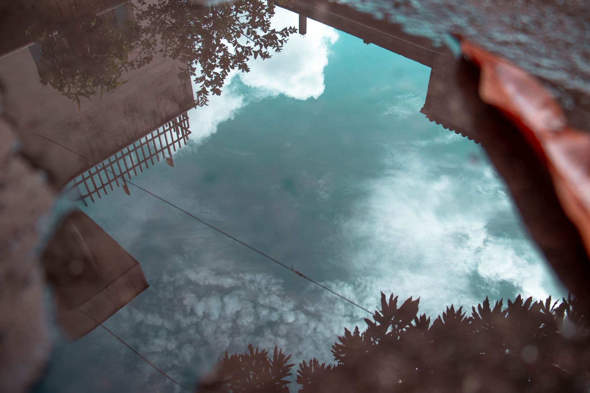 A serene reflection of clouds and trees in a puddle, capturing urban tranquility.