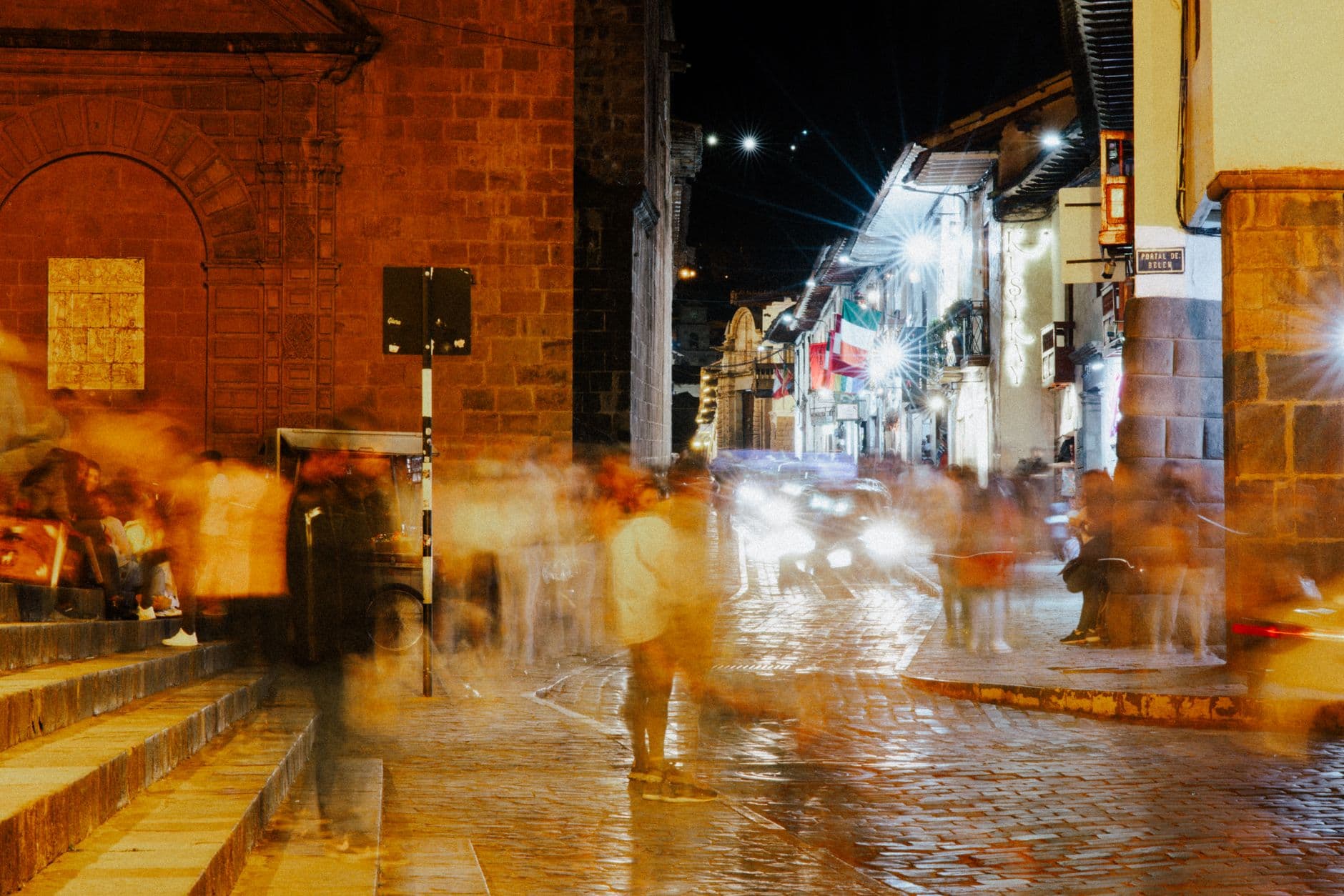 Blurred motion captures bustling nightlife in Cusco, Peru's historic cobblestone streets.