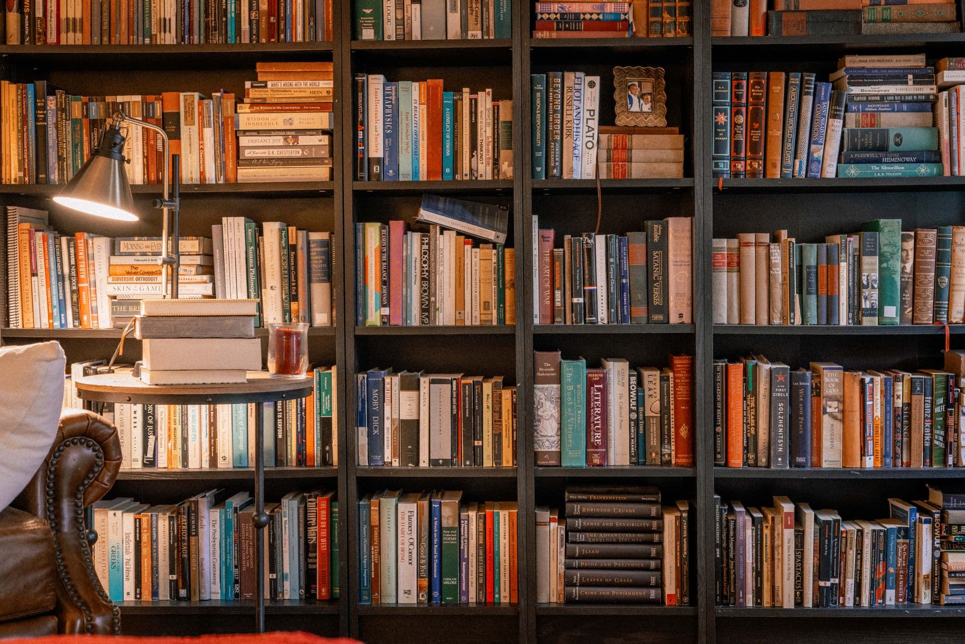 A warm, inviting library scene featuring a bookshelf, books, and a reading lamp.