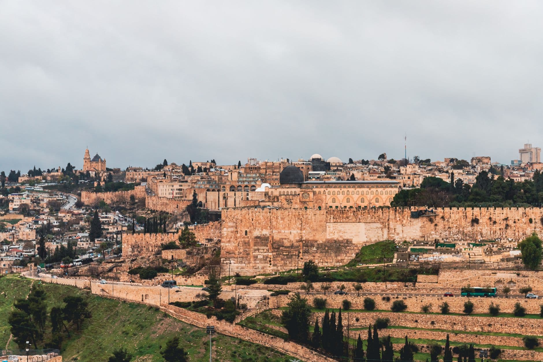 View of Jerusalem showcasing the ancient city walls and iconic architecture under a cloudy sky.