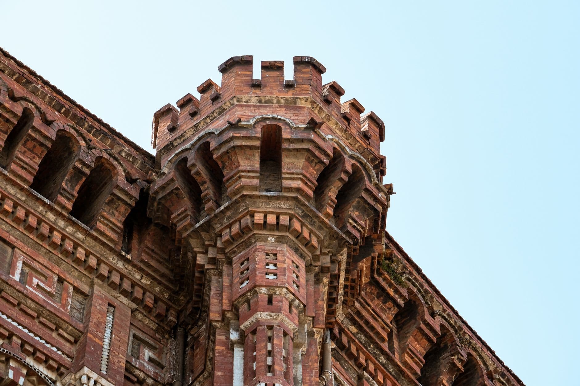 Close-up of a gothic architectural brick tower against a clear blue sky.