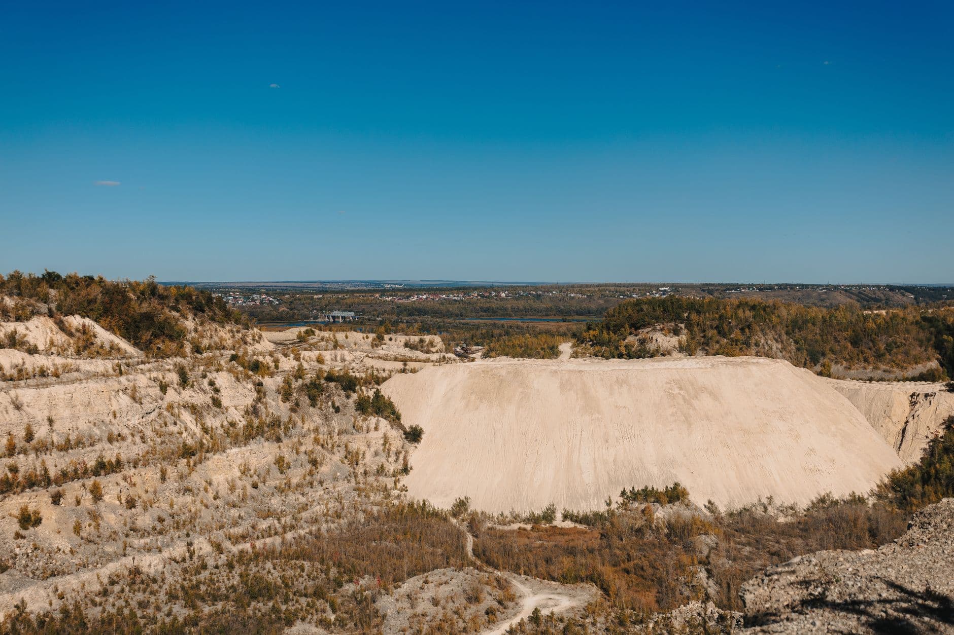 Expansive view of a quarry landscape with clear blue sky, showcasing natural beauty and industrial terrain.