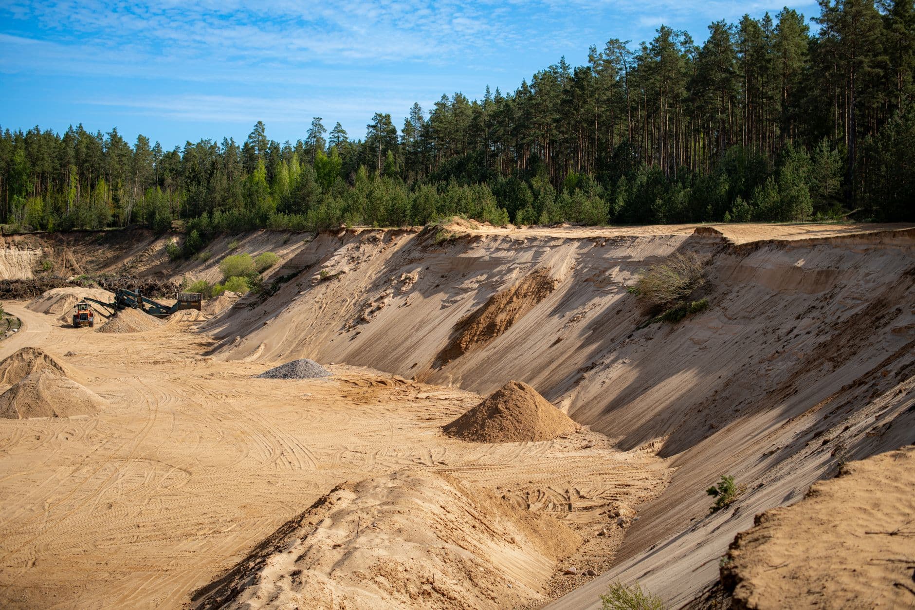 Explore a serene quarry landscape in Lithuania, surrounded by dense pine forests and bright sandy dunes.