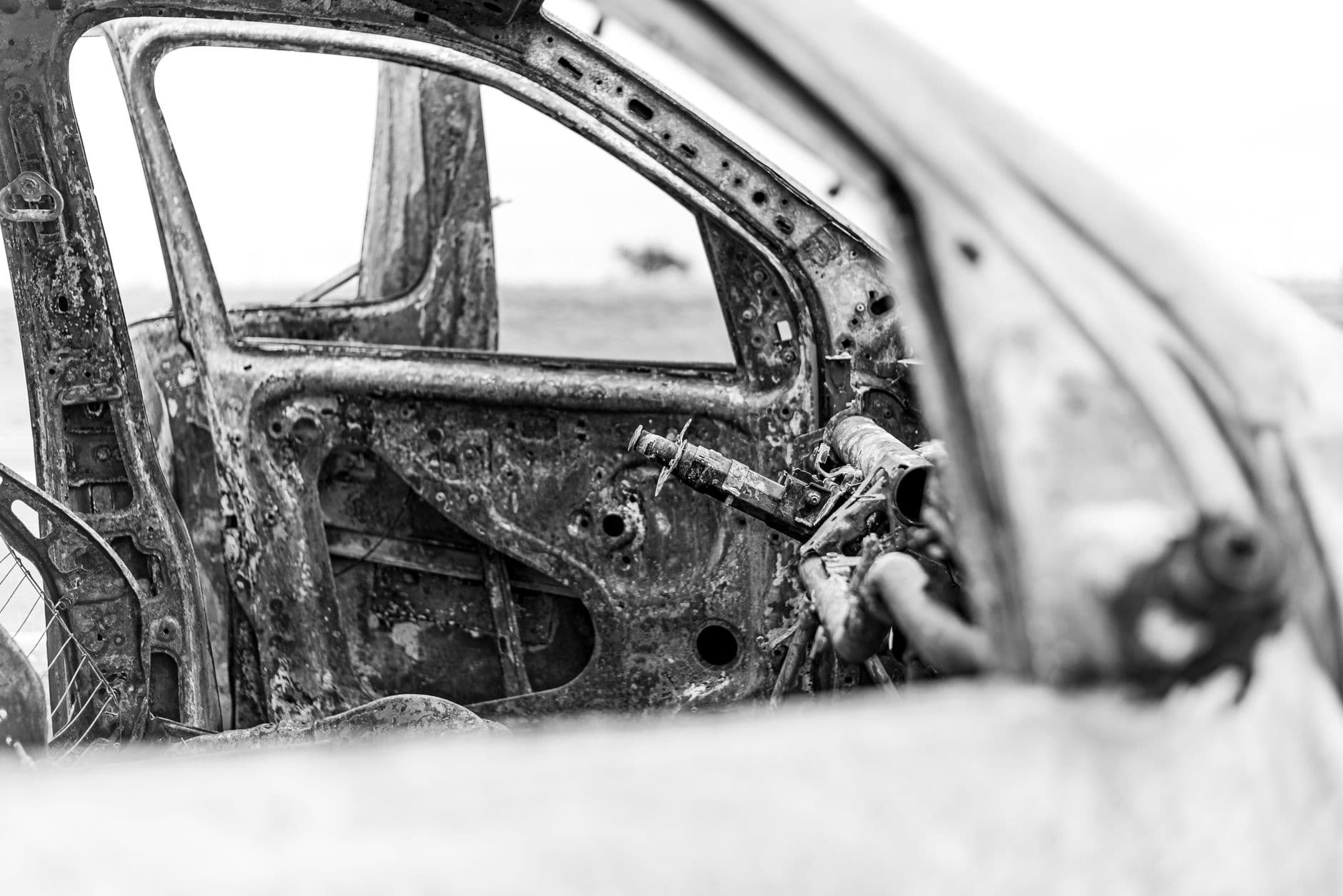 Detailed black and white photograph of a rusted, abandoned car interior frame capturing urban decay.