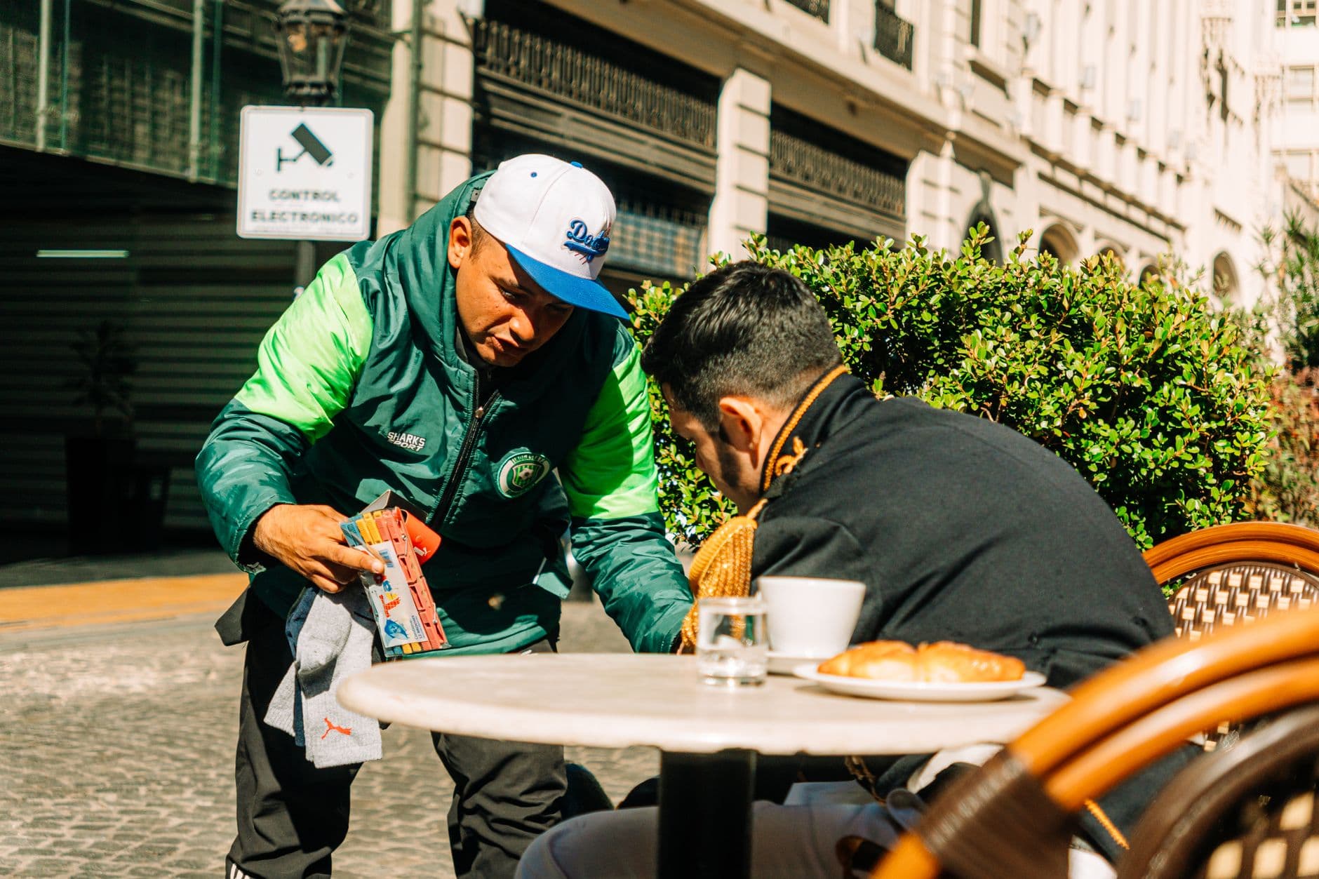 Street vendor interacts with customer at a Buenos Aires café, capturing urban life.