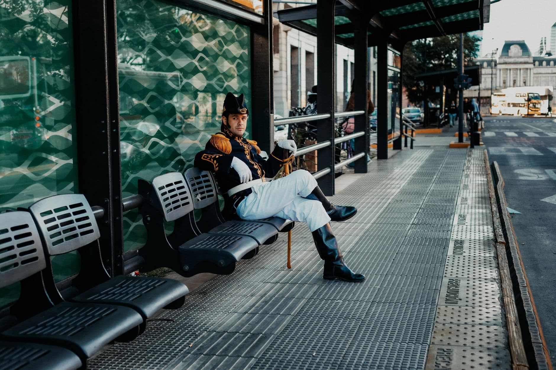 A colonial guard in uniform sits at a Buenos Aires bus stop, capturing historical essence.