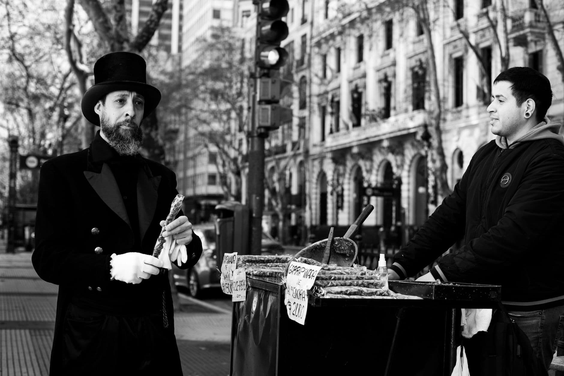 A man in formal attire buys food from a street vendor in Buenos Aires.