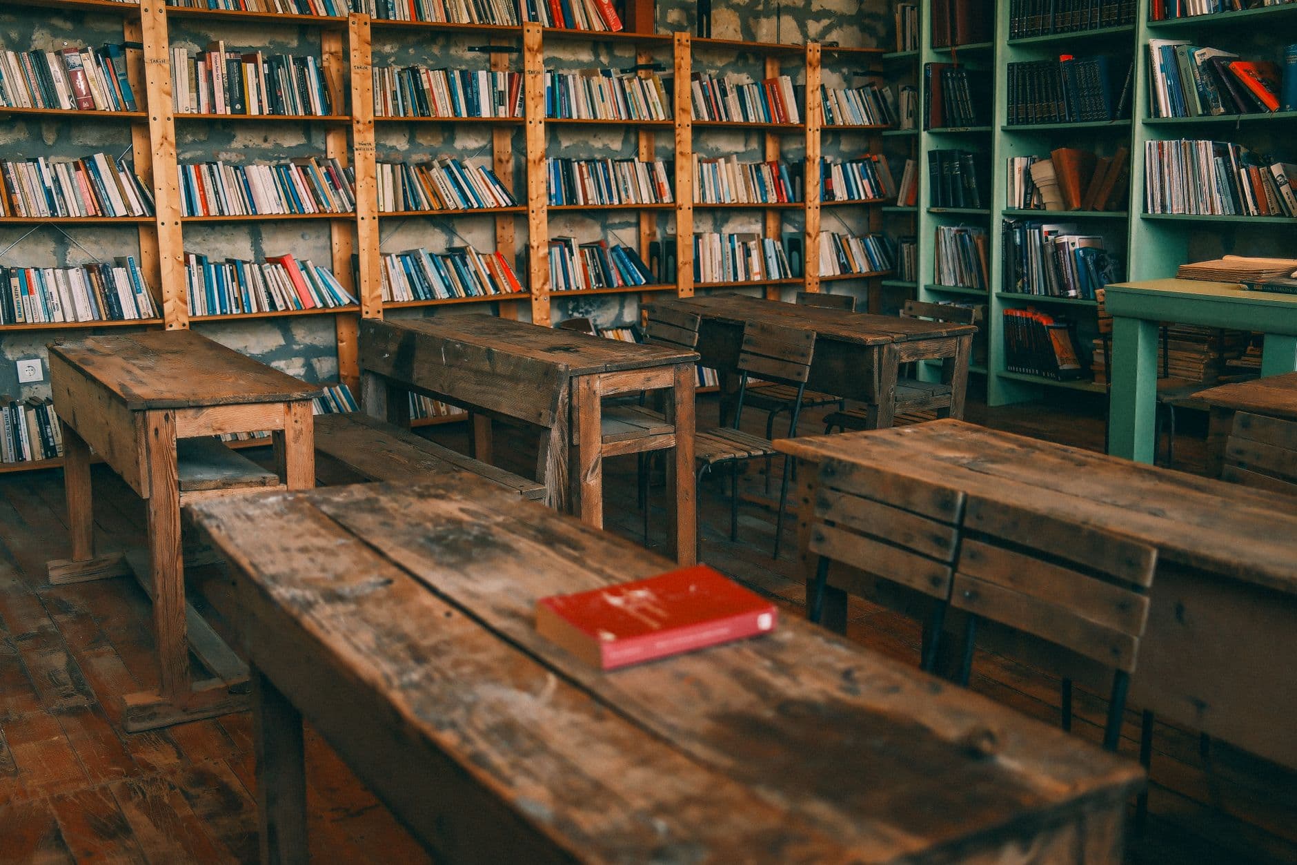 A vintage classroom with wooden desks and bookshelves filled with books, creating an academic atmosphere.