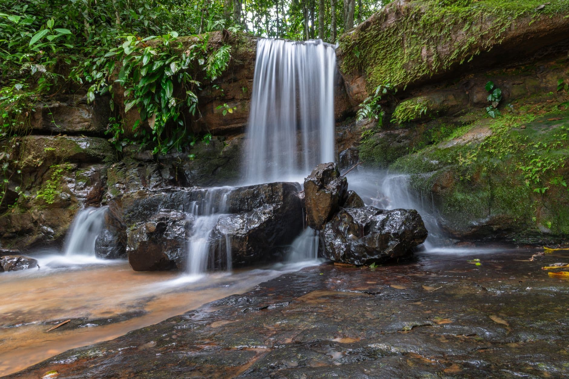 A tranquil waterfall cascading over rocks surrounded by lush greenery in Costa Rica's tropical jungle.