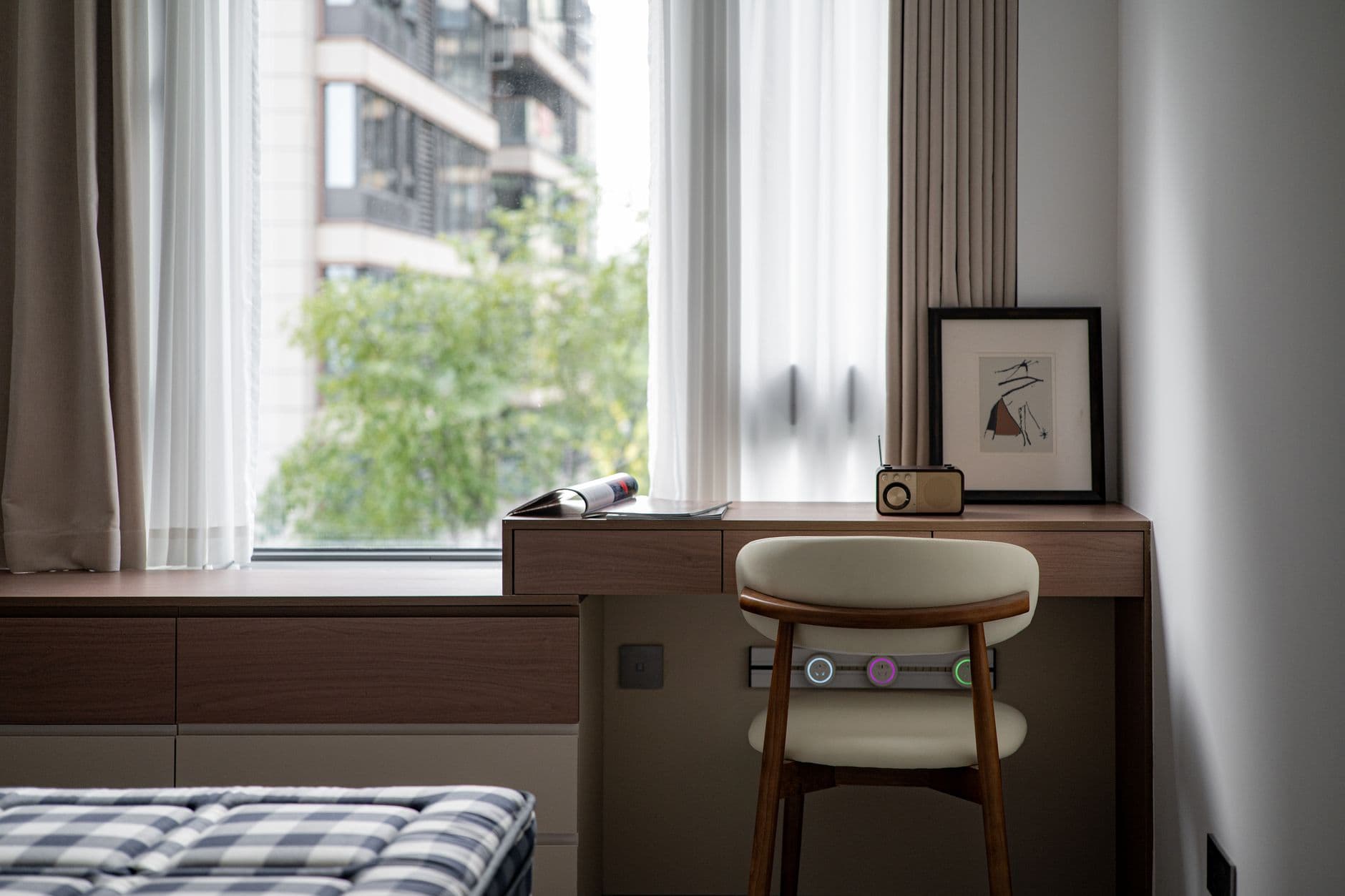 Stylish home workspace with desk, chair, and decor near window with city view.