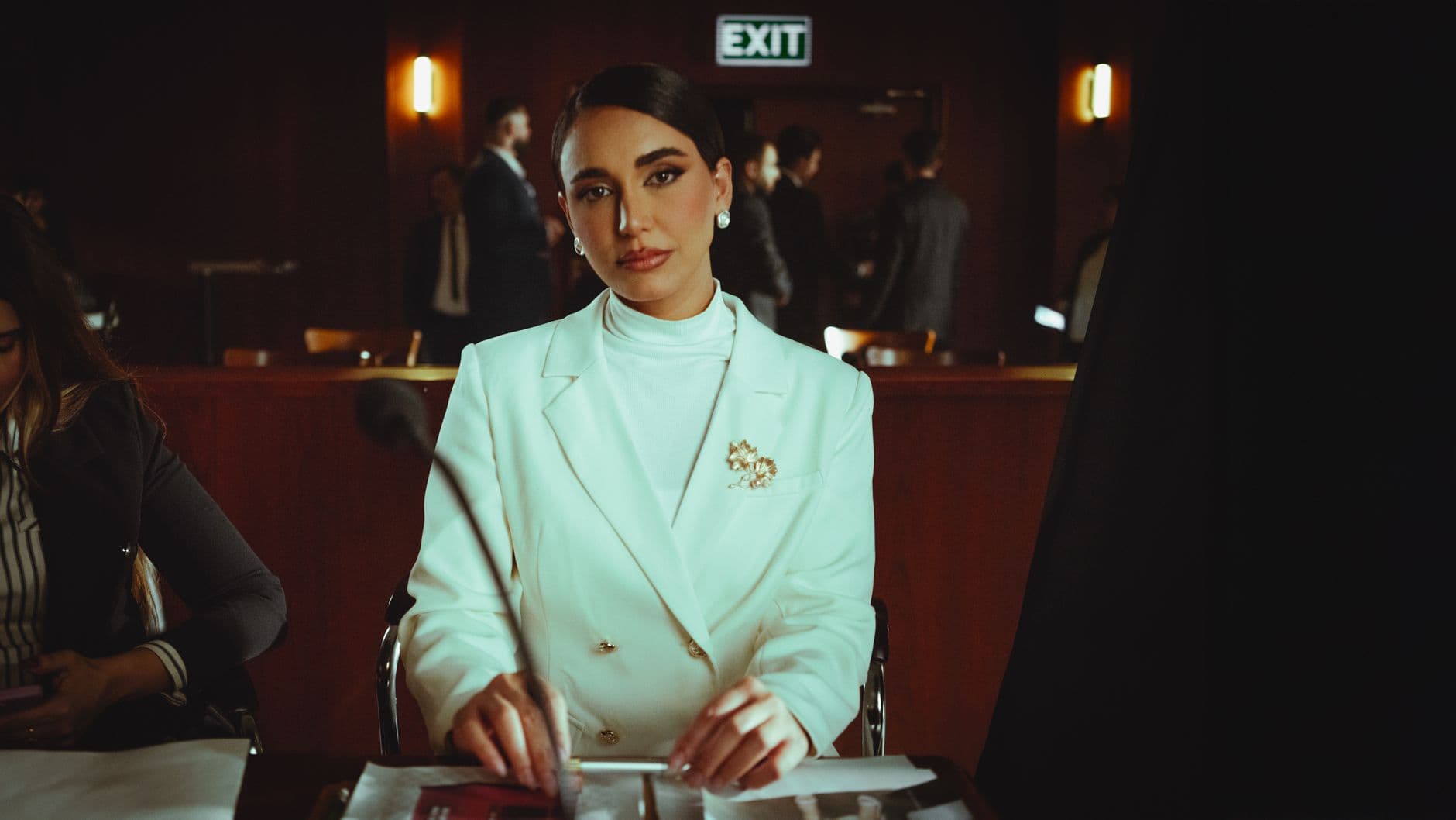 Elegant woman in a white suit attending a formal meeting in a conference room.