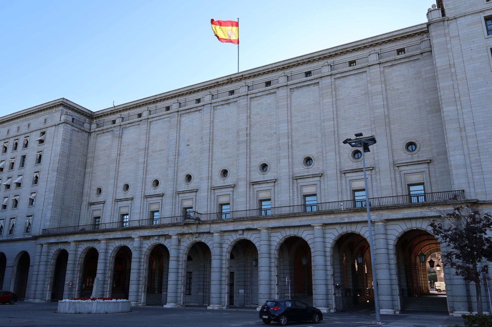 Exterior of a historic government building in Spain with a Spanish flag atop.