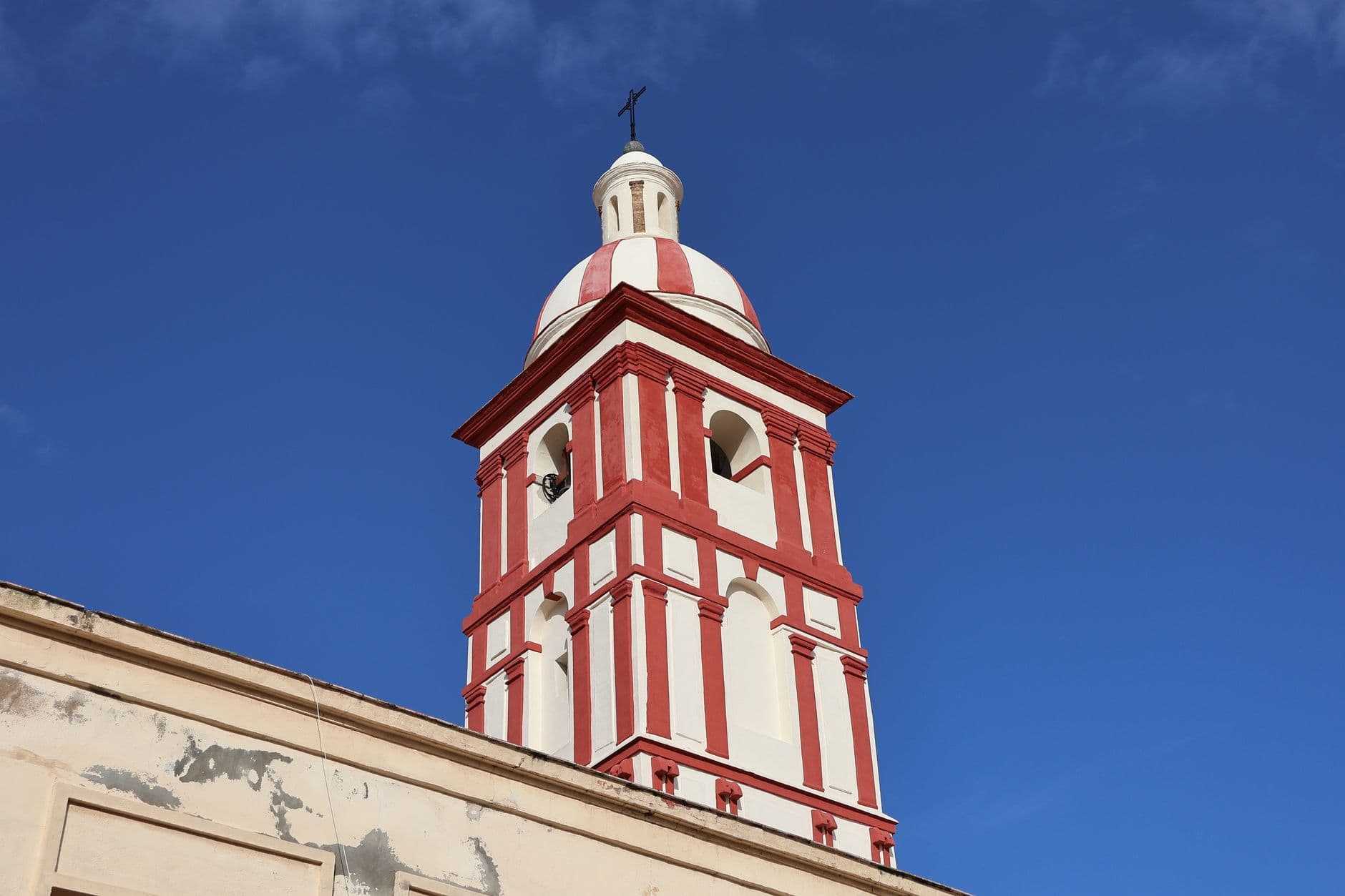 Close-up of a historic church tower in Cádiz, Spain, under a clear blue sky.