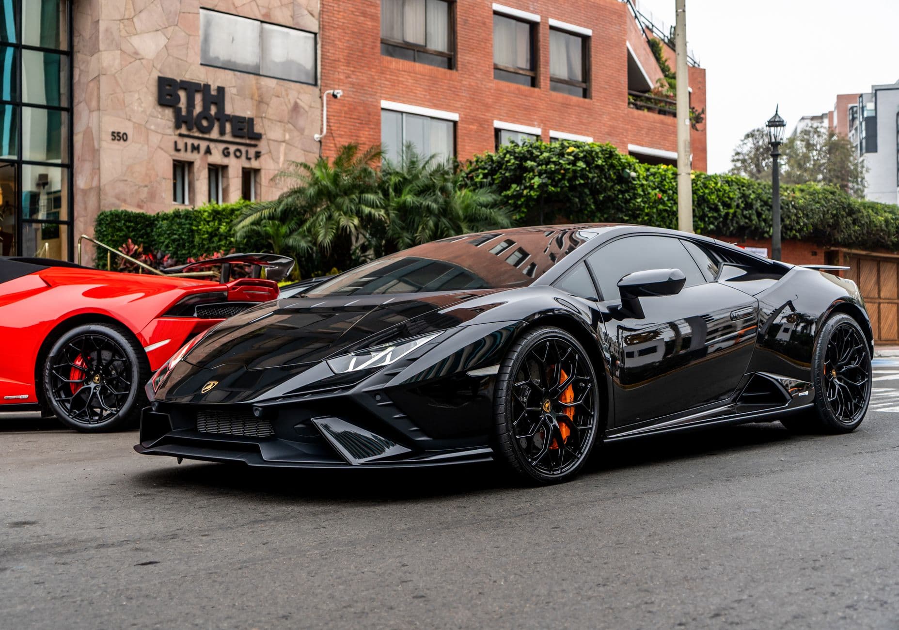 Sleek black and red sports cars parked outside BTH Hotel in Lima, Peru.