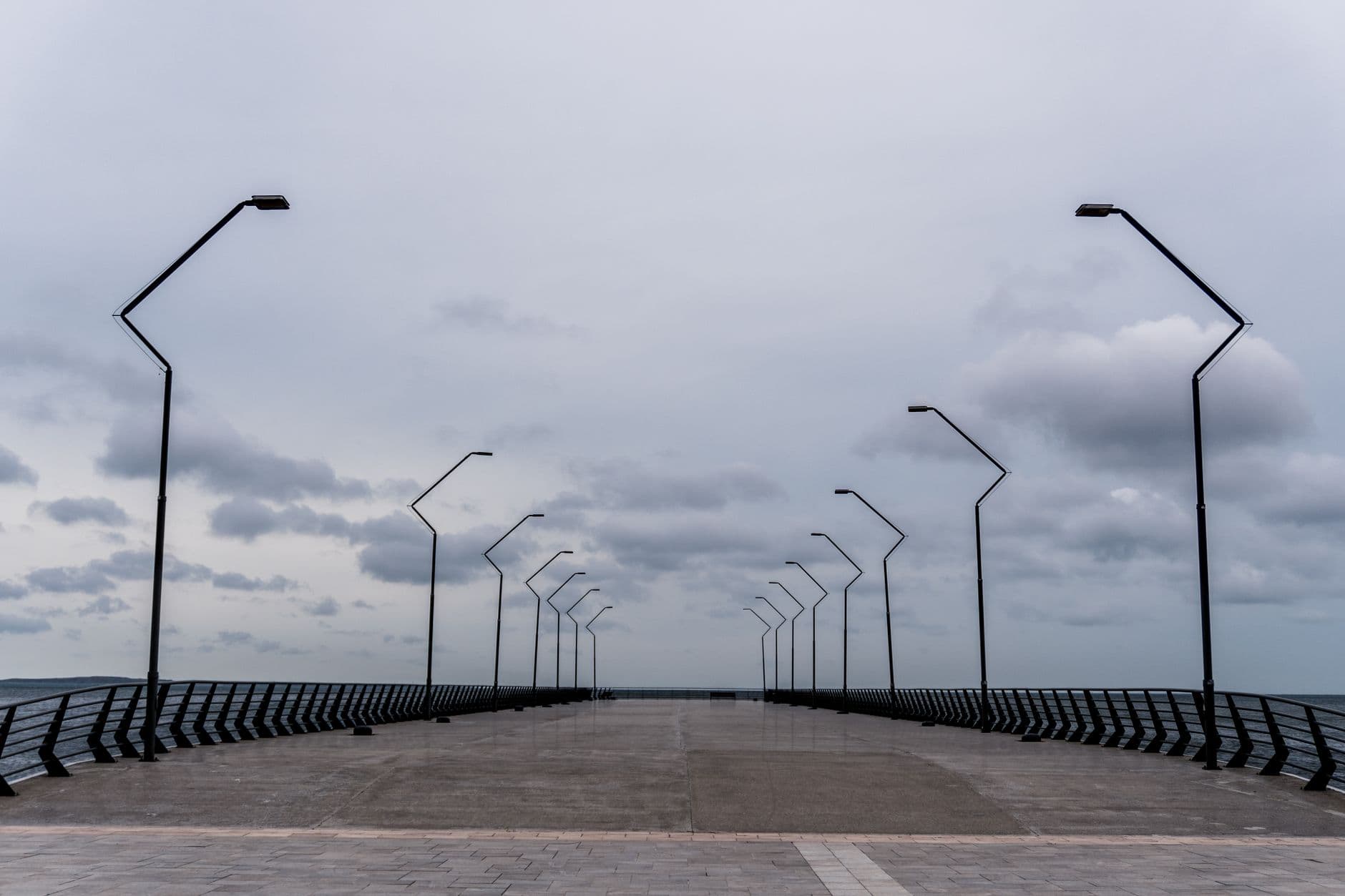 A symmetrical view of a modern pier with streetlights against a cloudy sky in Baku, Azerbaijan.