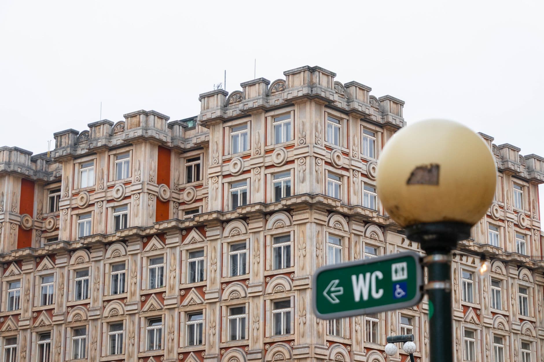 Detailed view of a historic building with ornate architectural features and a WC sign in the foreground.