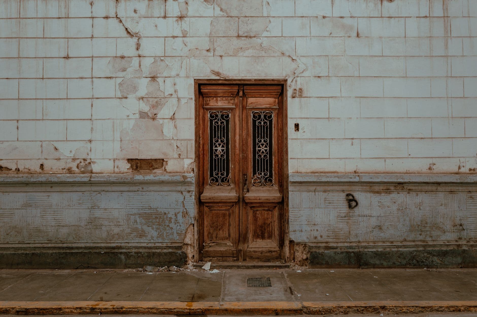 A rustic wooden door set in a weathered wall in Pacasmayo, Peru, showcasing historic architecture.