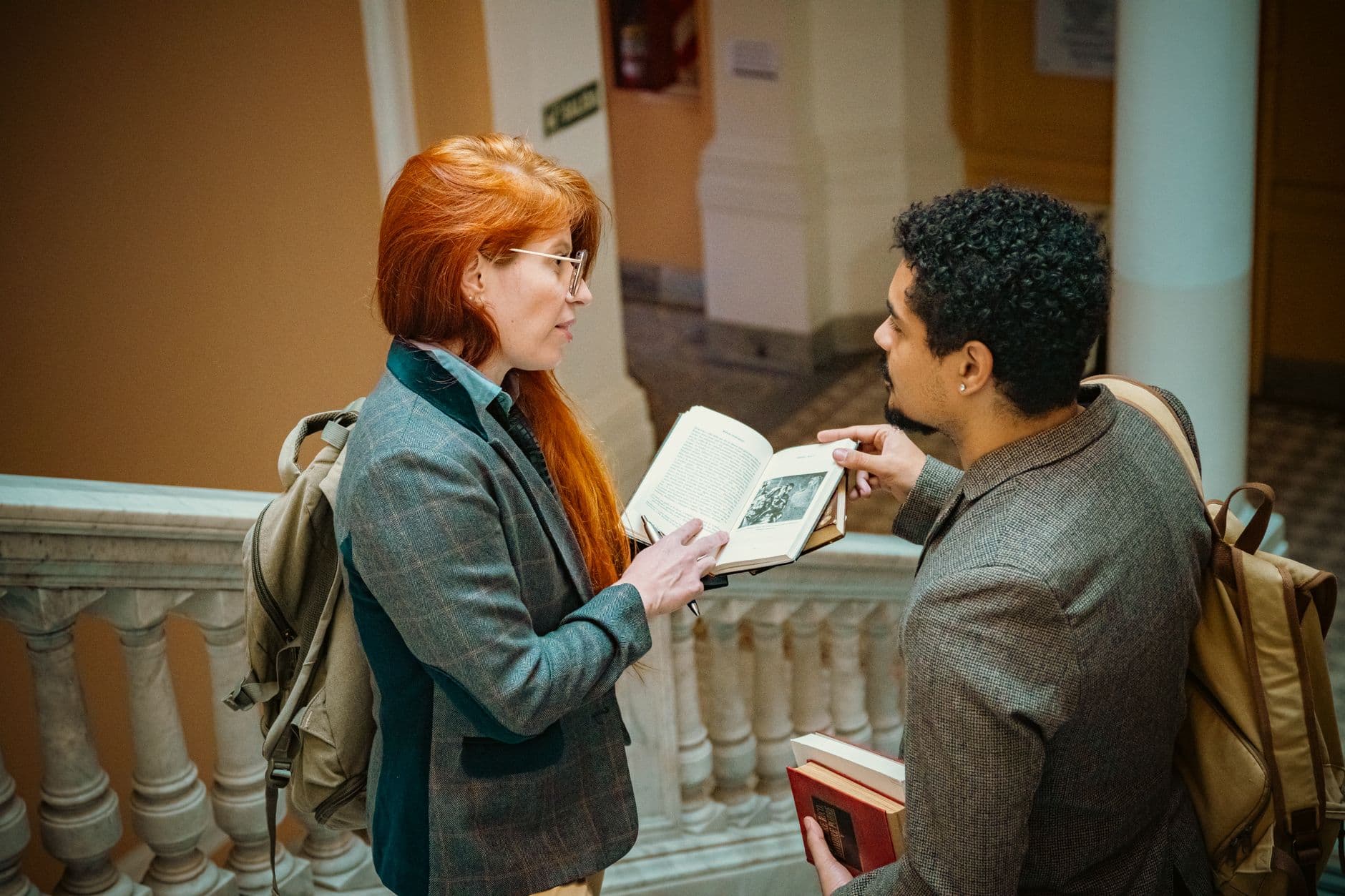 Two adults engage in a book discussion in a Buenos Aires hallway, showcasing diverse education.