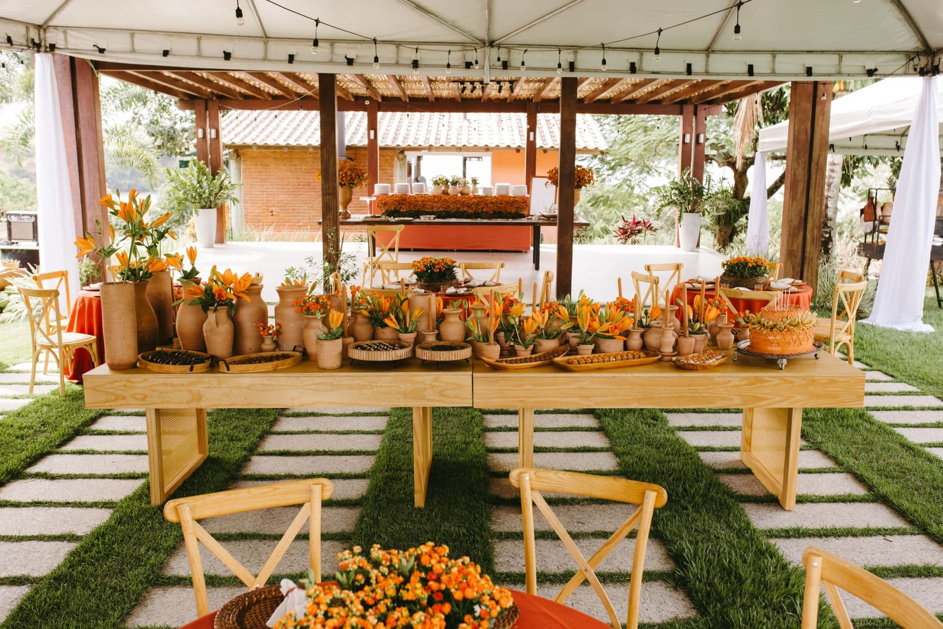 Beautiful outdoor wedding setup with terracotta decor and vibrant floral arrangements on wooden tables.