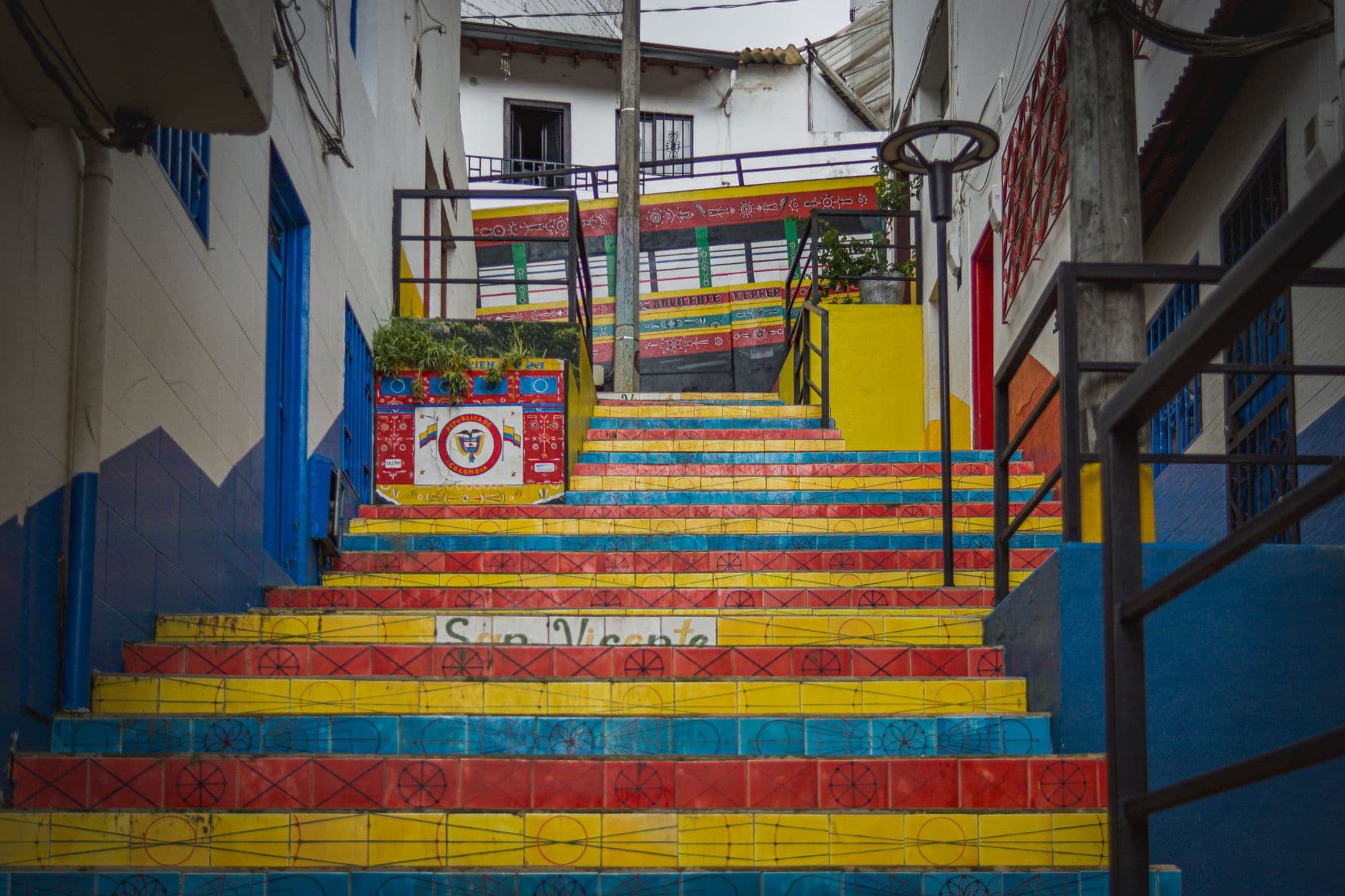 A vibrant staircase adorned with bright colors and patterns in an urban alleyway, offering a lively cultural ambiance.