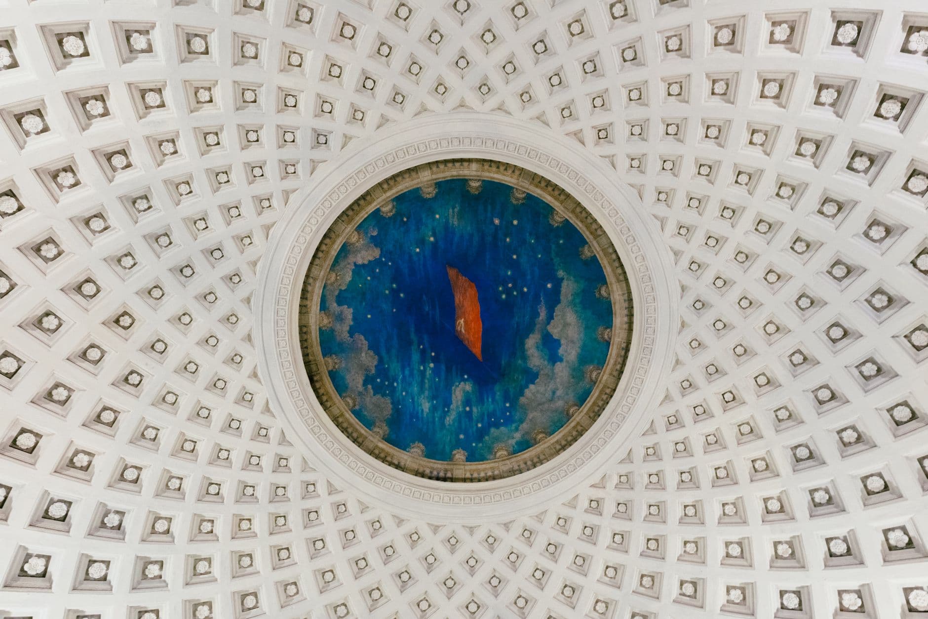 A detailed view of an ornate dome ceiling featuring a colorful artistic centerpiece in an architectural landmark.