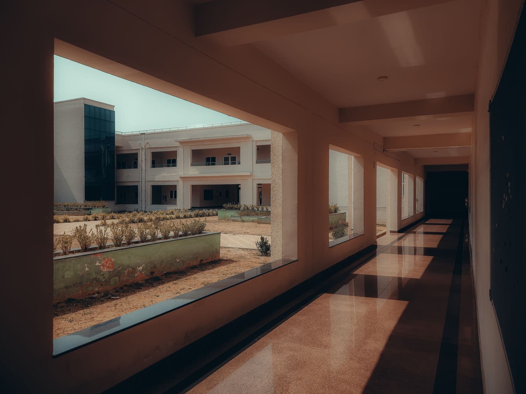 A bright and spacious school corridor with a view of the courtyard and modern architecture.