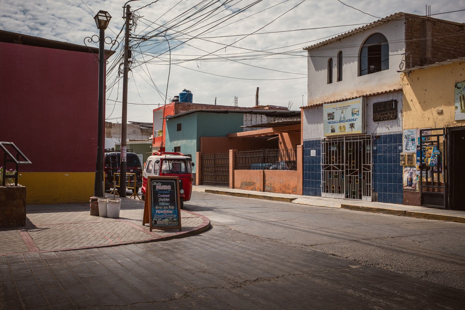 Eye-catching urban scene showcasing colorful buildings, vintage vehicles, and local shops on a bright day.