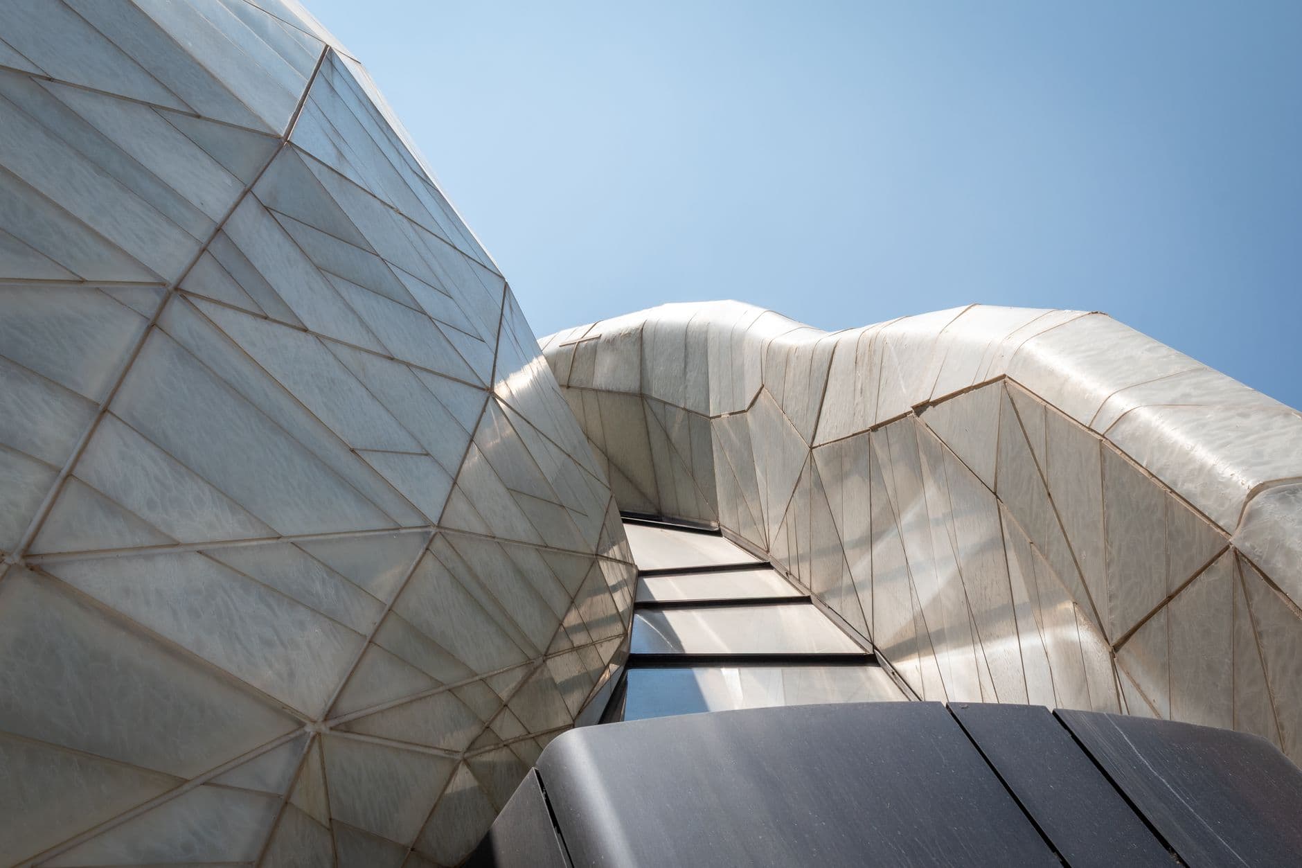 Close-up view of a unique geometric building facade in Santiago, Chile with a clear blue sky.