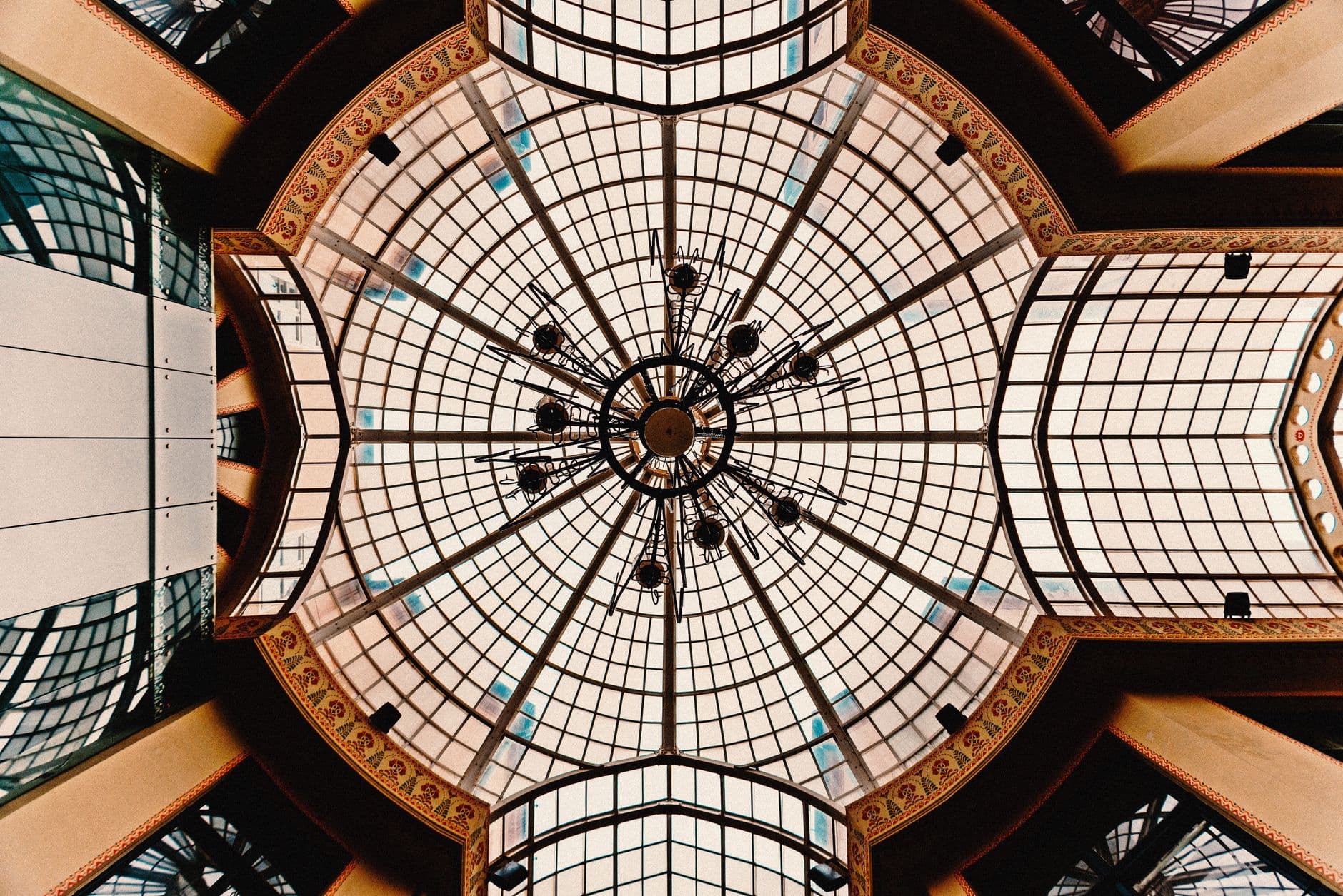 A stunning glass dome ceiling with intricate patterns in Oradea, Romania, captured from below.