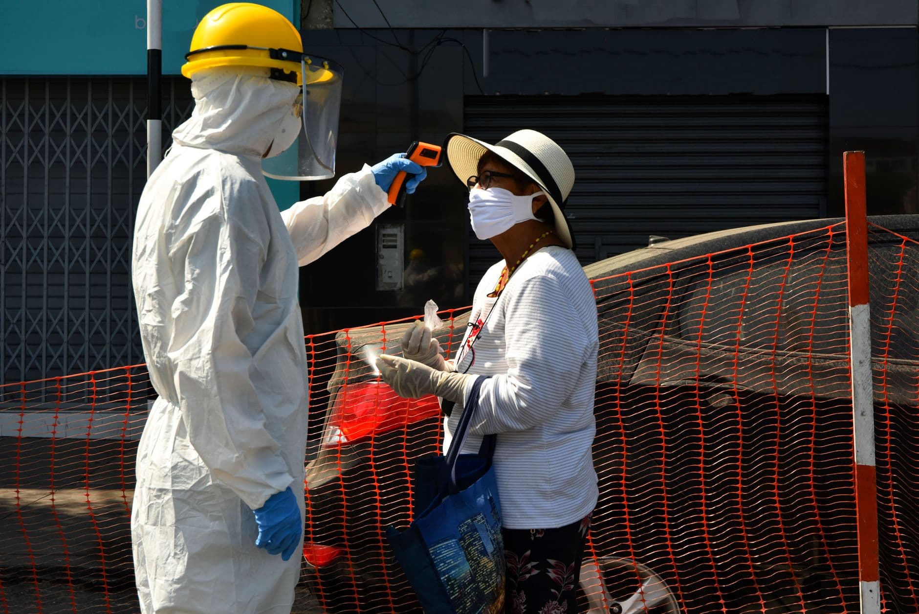 Healthcare worker checks woman's temperature during COVID-19 pandemic in Lima, Peru.
