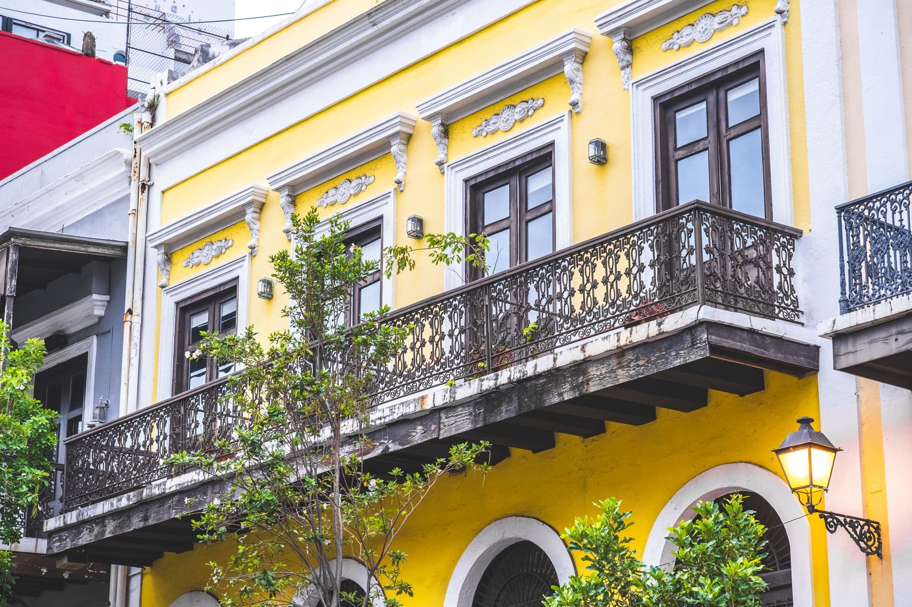 Vibrant yellow townhouse with ornate iron balcony and classic architectural details.