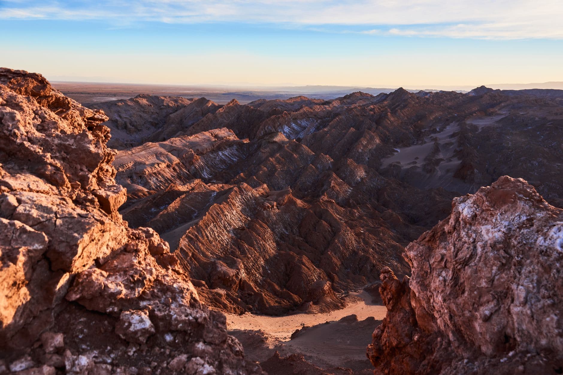 Stunning view of a rugged canyon landscape at sunset, highlighting dramatic rock formations and eroded terrain.