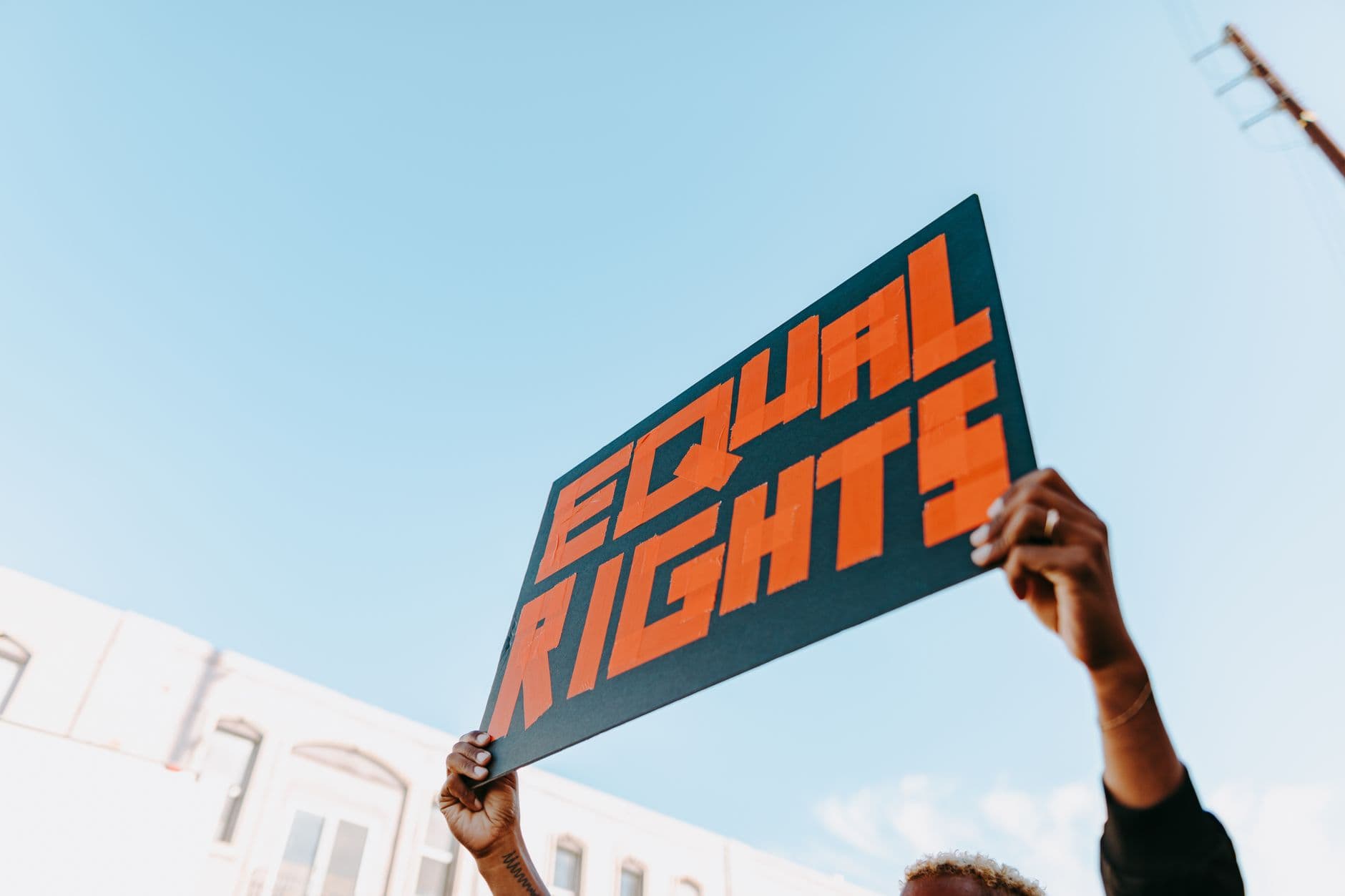 Hands holding a bold equal rights sign at an outdoor protest.
