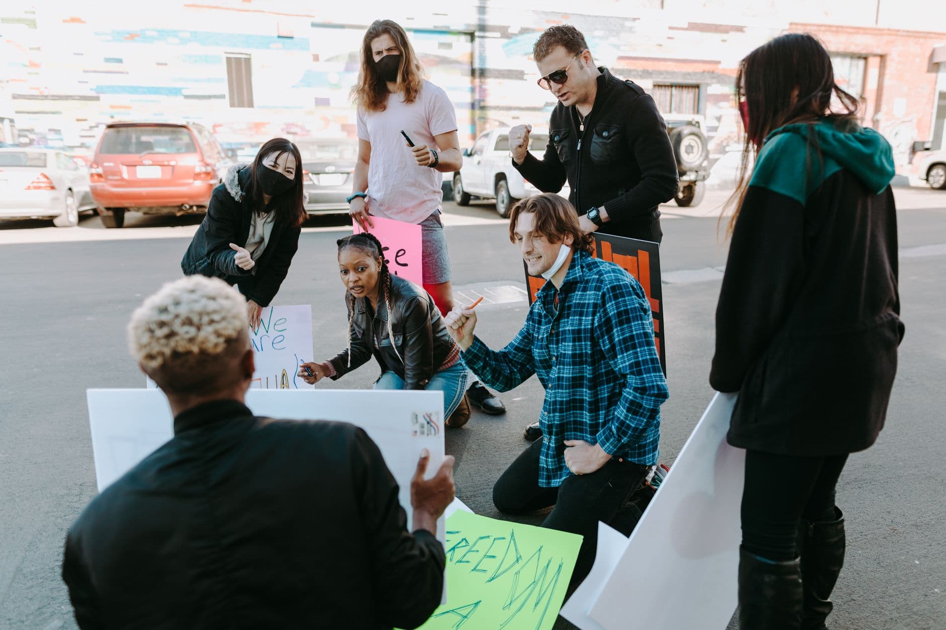 Diverse group of activists preparing protest signs outdoors, signifying unity and activism.