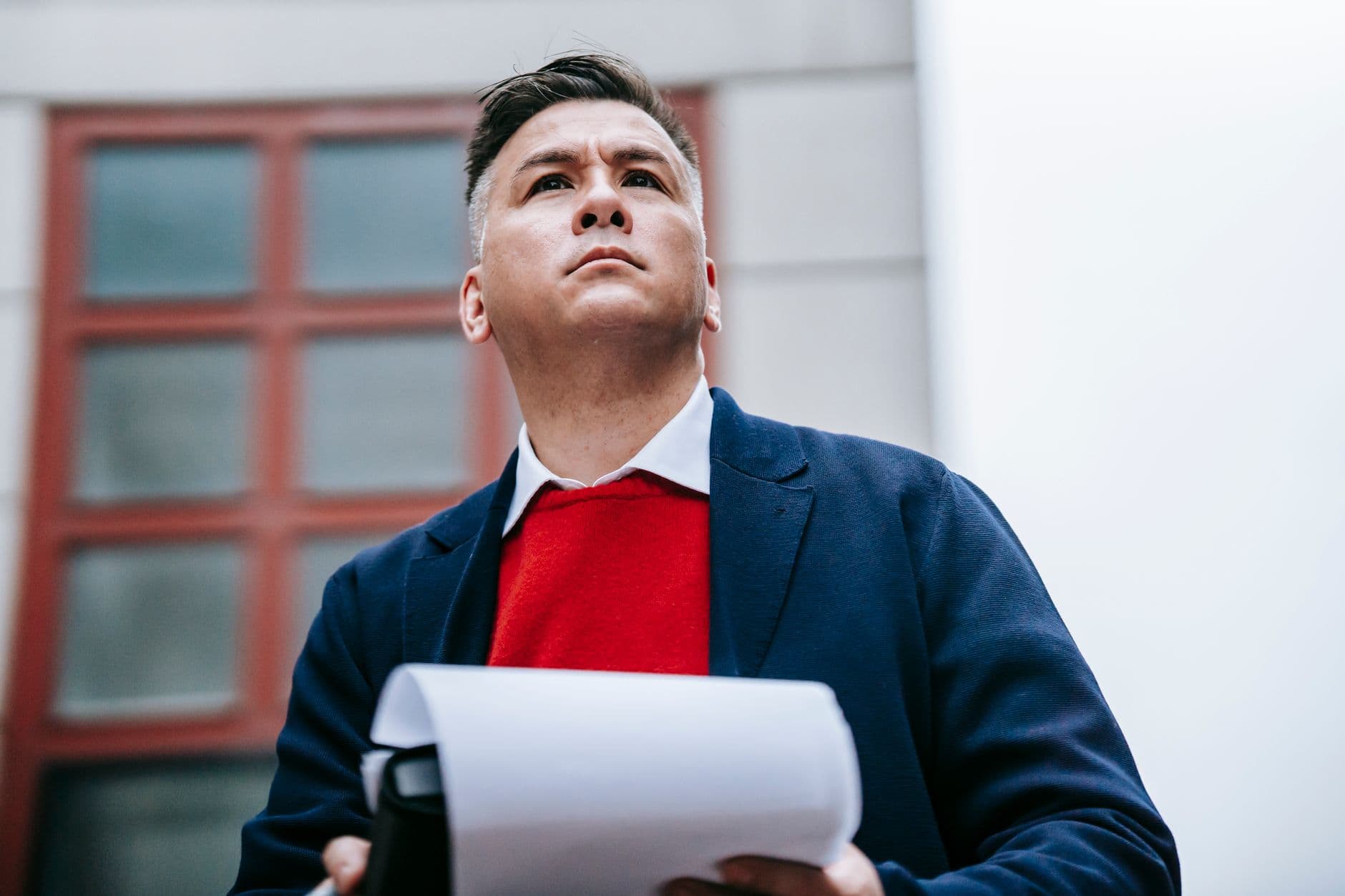 Business professional standing outdoors, confidently holding documents in a stylish outfit.