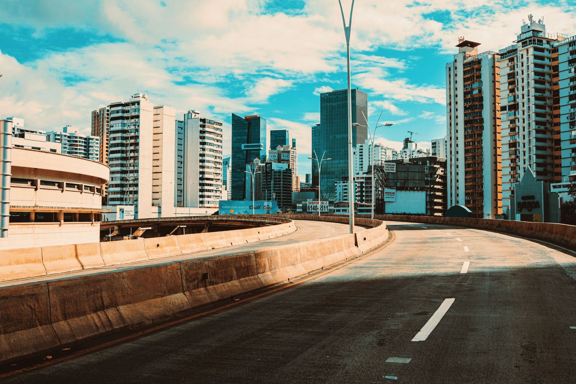 Empty highway with a view of Panama City's modern skyline under a bright sky.