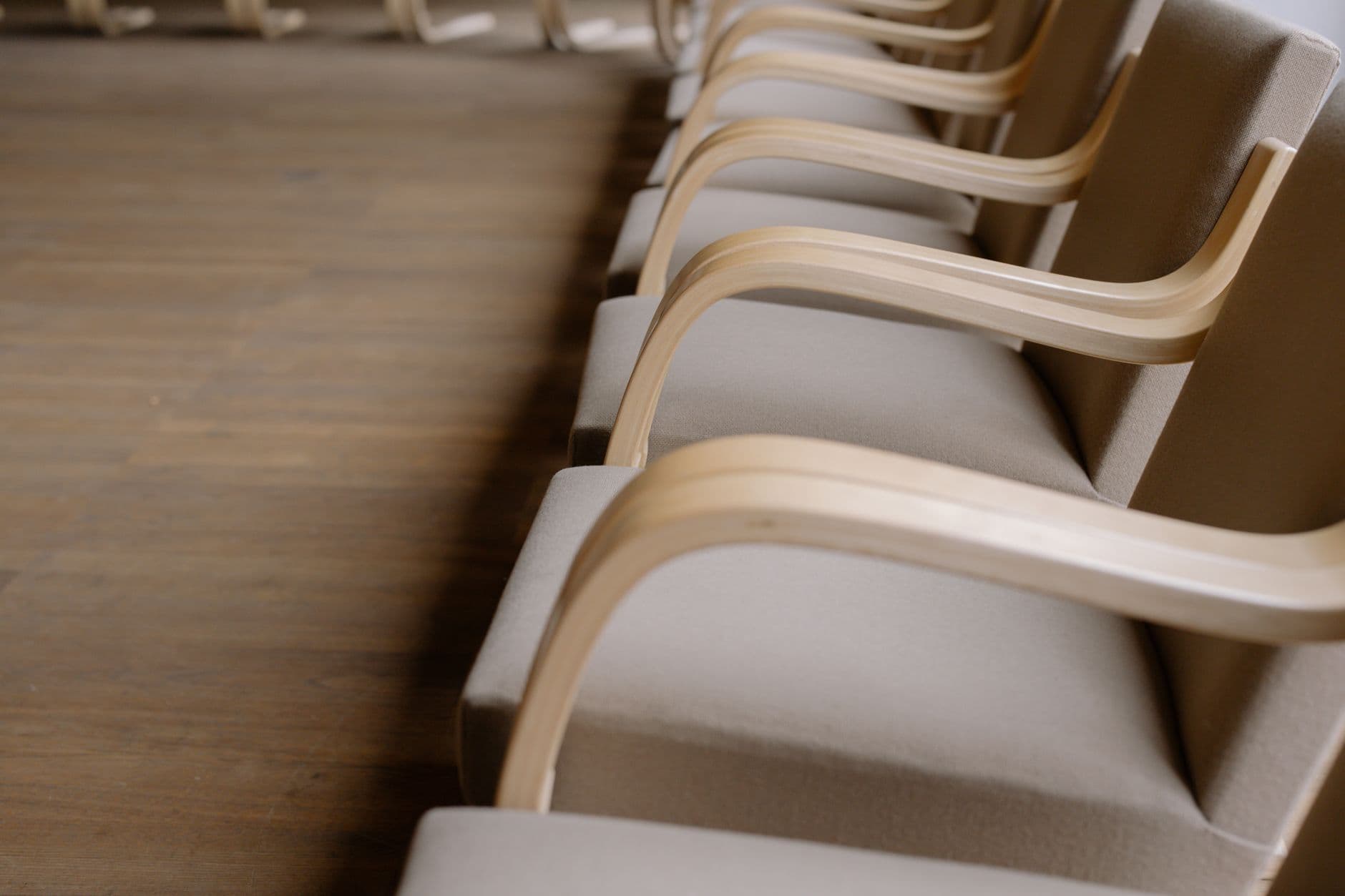 Row of modern wooden arm chairs in an empty conference room with minimalist design.