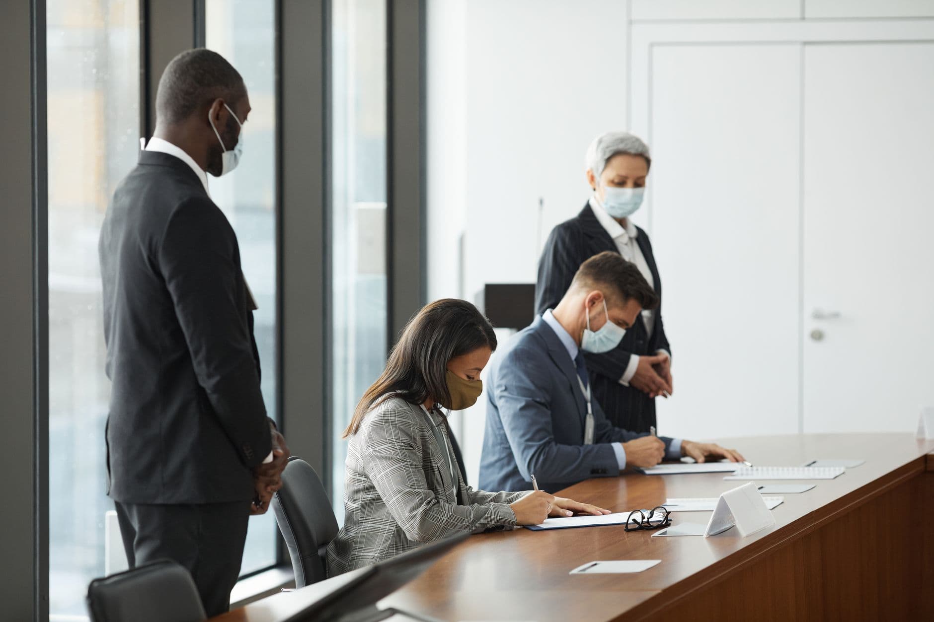 Professionals in a corporate meeting wearing masks for COVID-19 safety protocols.