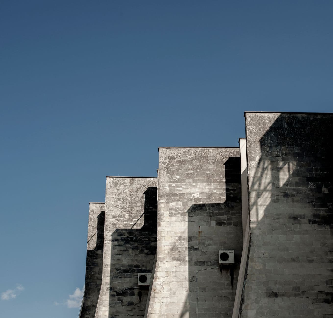 Shadows on a modern stone building facade under clear blue sky in Lviv, Ukraine.