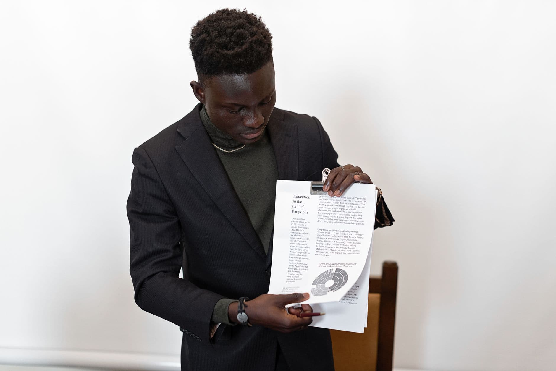 African American man in blazer presenting a report with documents, showcasing confidence and professionalism.