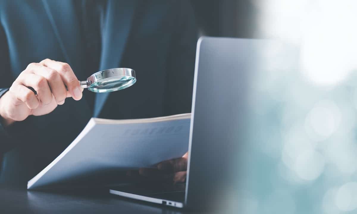 Businessman holding a magnifying glass,Audit Document Concepts, quality assessment management With a checklist, business document evaluation process, market data report analysis and consulting